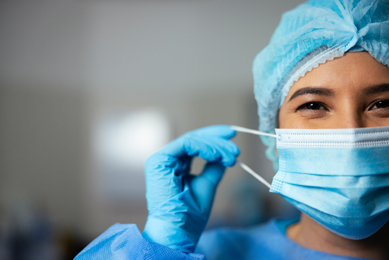 Face, doctor and woman in theatre at hospital for surgery healthcare and emergency for medical care and support. Surgeon, happy and specialist in disposal gown for procedure at work to cure disease